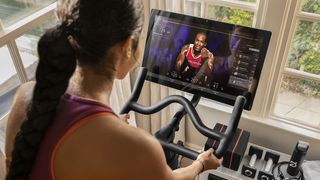 Woman using a Peloton bike indoors